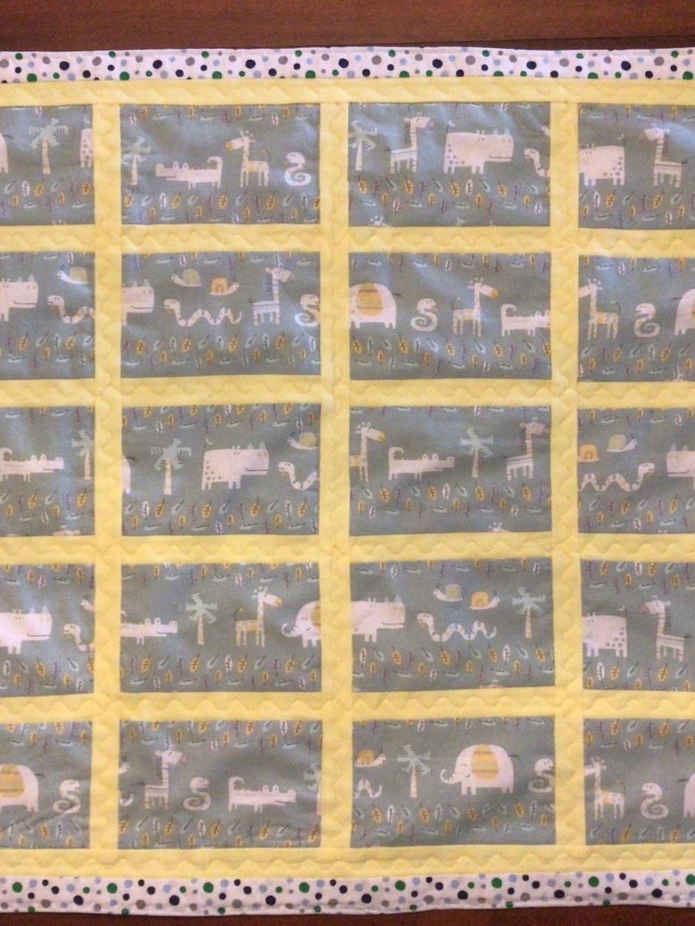 Baby quilt  27” x 22”. Light green, yellow, polka dot border & grey backing